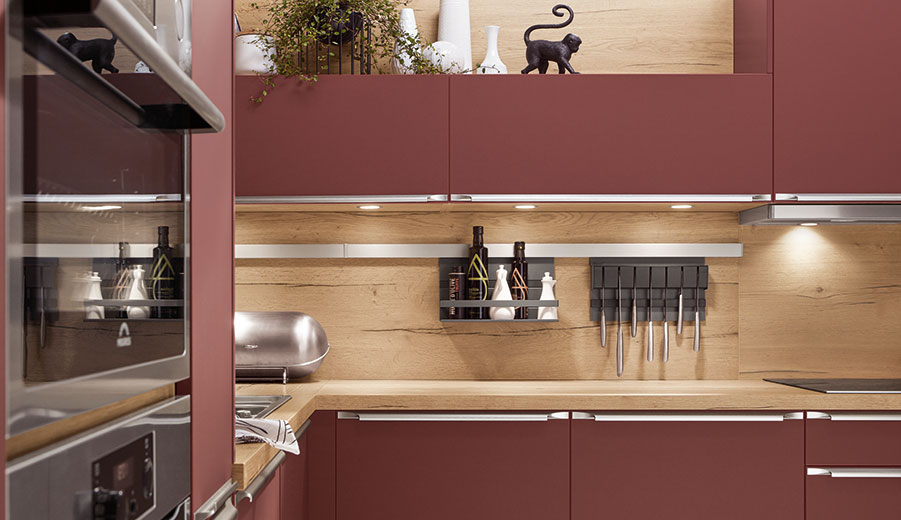 Modern kitchen with warm wood accents, sleek maroon cabinets, and stainless-steel appliances, highlighted by under-cabinet lighting and a playful cat silhouette.